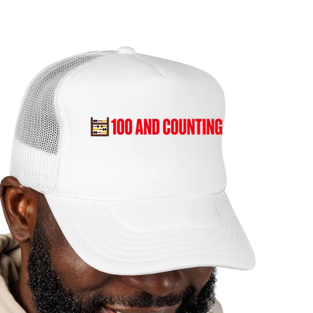 A tiny abacus beside 100 AND COUNTING, on a white foam trucker hat