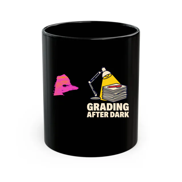 A desk lamp over a pile of papers, GRADING AFTER DARK, on a black mug