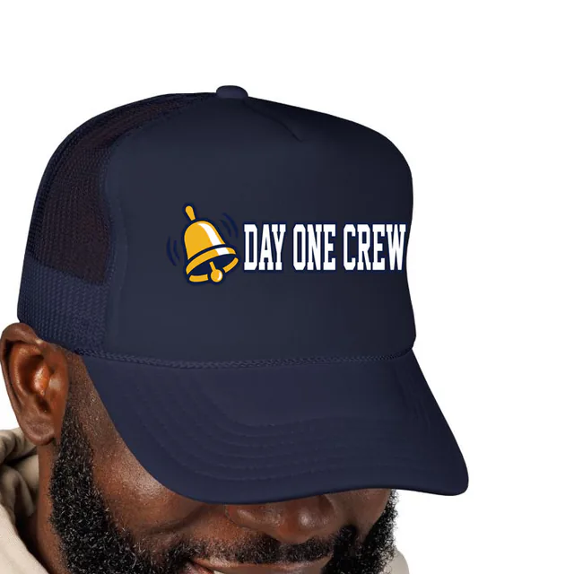 A ringing school bell beside DAY ONE CREW, on a navy foam trucker hat
