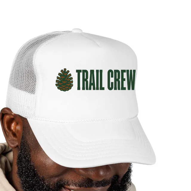 A pinecone beside TRAIL CREW, on a white foam trucker hat
