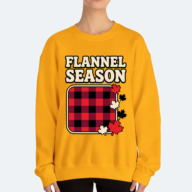 A buffalo-check square and falling leaves, FLANNEL SEASON, on a gold adult crewneck