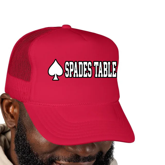 A playing card spade beside SPADES TABLE, on a red foam trucker hat
