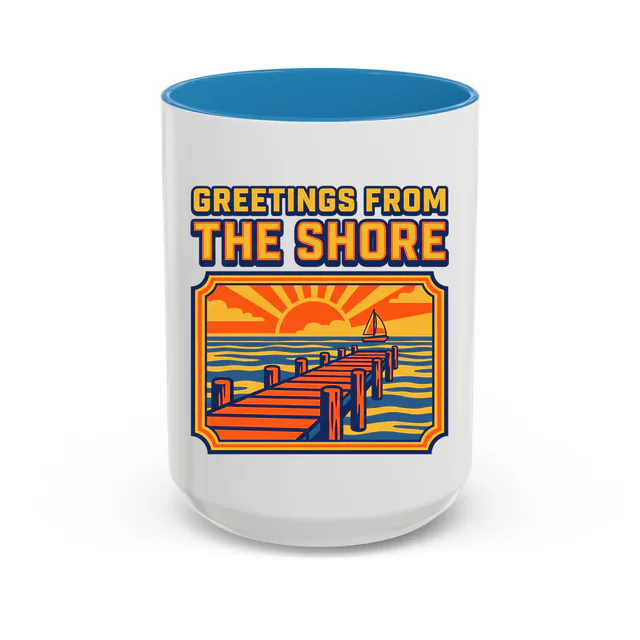 A postcard of a pier and a sailboat, GREETINGS FROM THE SHORE, on a blue accent mug