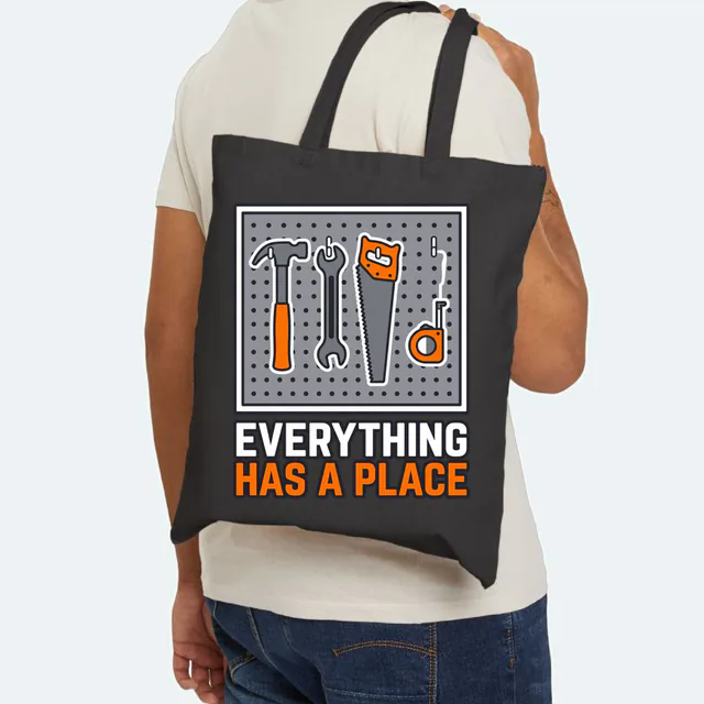 Tools in their outlines on a pegboard, EVERYTHING HAS A PLACE, on a black canvas tote