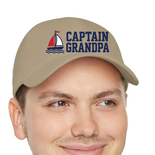 A little sailboat beside CAPTAIN GRANDPA, on a khaki dad hat