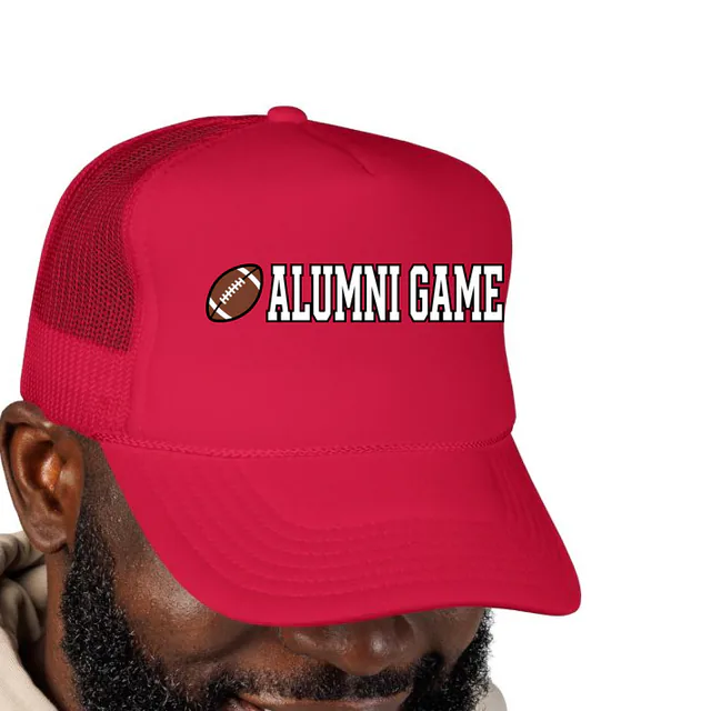 A small football beside ALUMNI GAME, on a red foam trucker hat