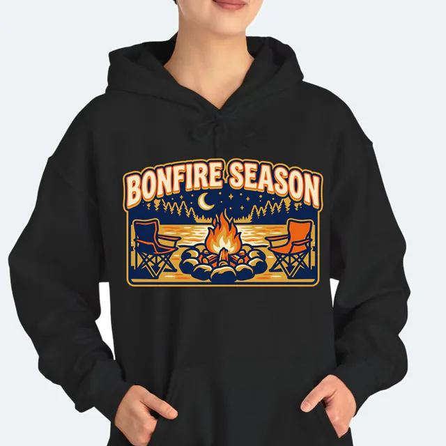 A lakeside bonfire under a crescent moon, BONFIRE SEASON, on a black adult hoodie