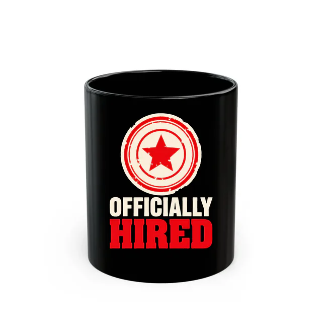 A round rubber stamp with a star, OFFICIALLY HIRED, on a black mug