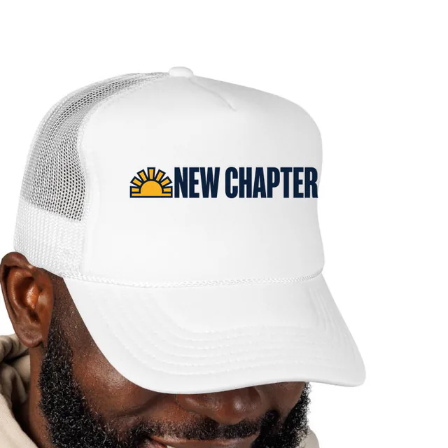 A rising sun beside NEW CHAPTER, on a white foam trucker hat