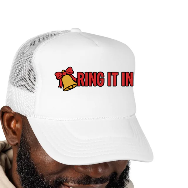A brass bell with a bow beside RING IT IN, on a white foam trucker hat