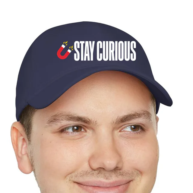 A tiny magnet beside STAY CURIOUS, on a navy dad hat