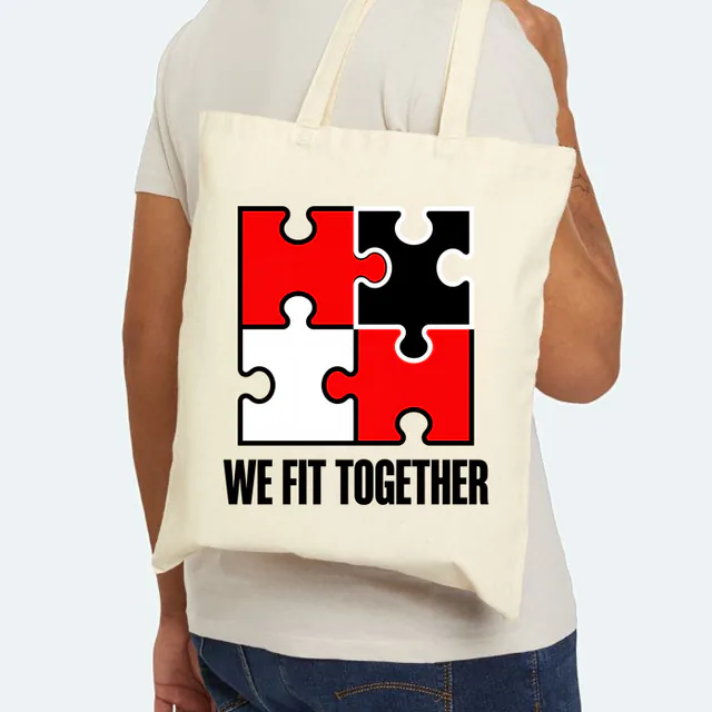 Four interlocking puzzle pieces, WE FIT TOGETHER, on a natural canvas tote
