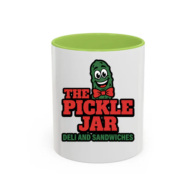 A grinning pickle in a bow tie, THE PICKLE JAR, on a light green accent mug