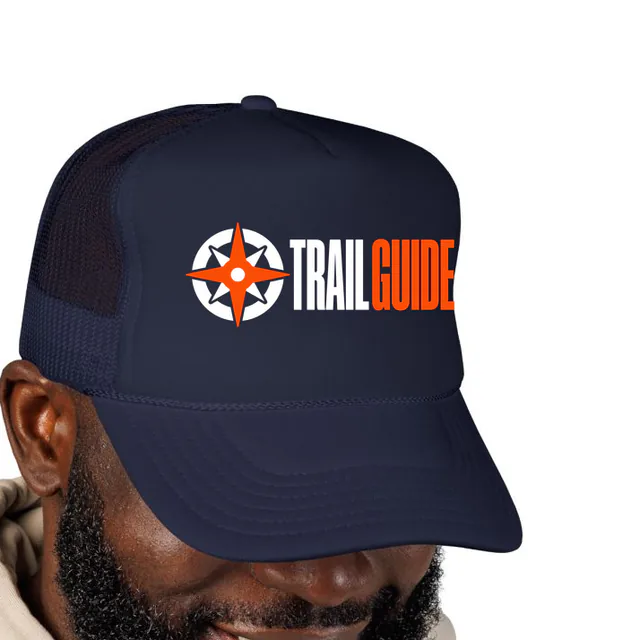 A compass rose beside TRAIL GUIDE, on a navy foam trucker hat