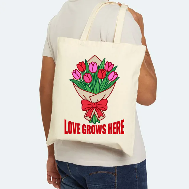 A wrapped bouquet of tulips, LOVE GROWS HERE, on a natural canvas tote