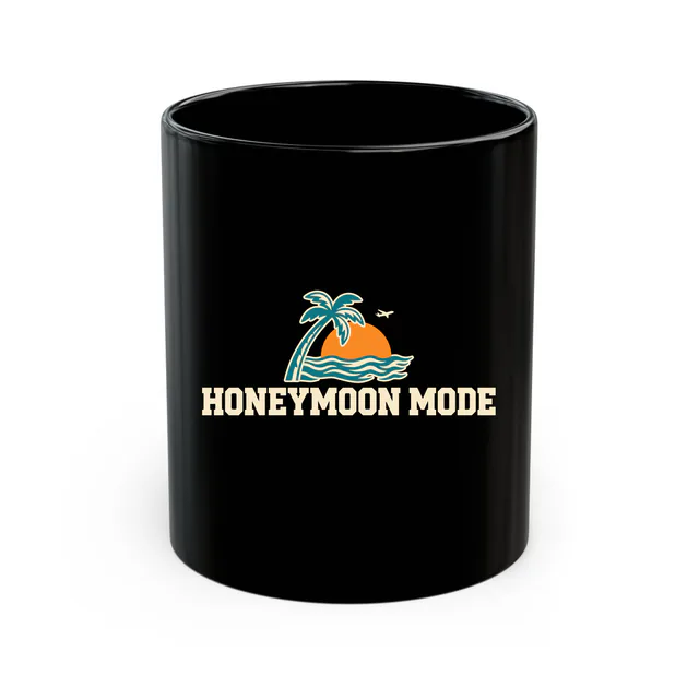 A palm tree and a setting sun, HONEYMOON MODE, on a black mug