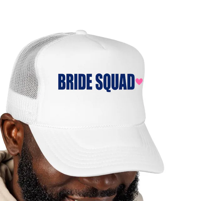 A pink heart beside BRIDE SQUAD, on a white foam trucker hat
